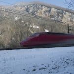 a red and white train on a track in the snow
